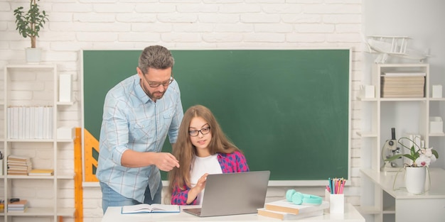 Ernsthaftes jugendlich Mädchen und Lehrermann in der High School mit PC an der Tafel in der Kindheit