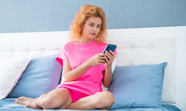 Ernsthaftes Mädchen entspannt sich zu Hause und schreibt SMS am Telefon Mädchen schreibt am Telefon im Bett SMS SMS an das Mädchen