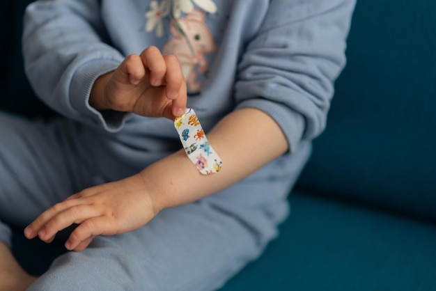 Foto ernte des kindes kleben ein bandaid auf wunde auf knien baby mädchen kleinkind trägt blauen kleber den patch mit