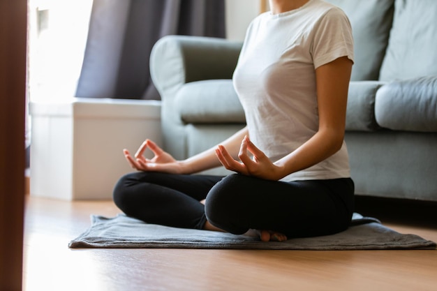 Ernte unerkennbare junge Frau, die zu Hause Yoga macht