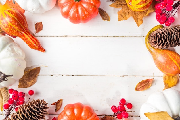 Erntedankfest, Halloween festliche Geetiing-Karte mit Kürbissen, dekorativen Beeren und Herbstblättern auf weißem Holztisch-Kopierraum. Herbstferien-Flatlay-Kopienraum