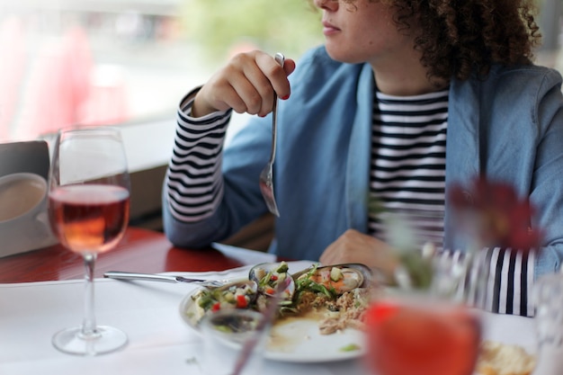 Erntefrau, die im Restaurant isst und auf das Fenster schaut