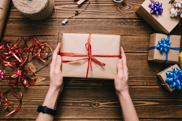 Erntehände, die eingewickeltes Geschenk auf dem Tisch halten