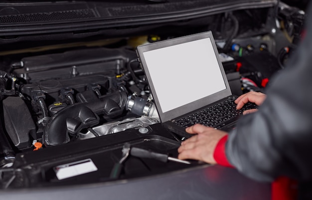 Erntemechaniker mit Laptop beim Reparieren des Autos