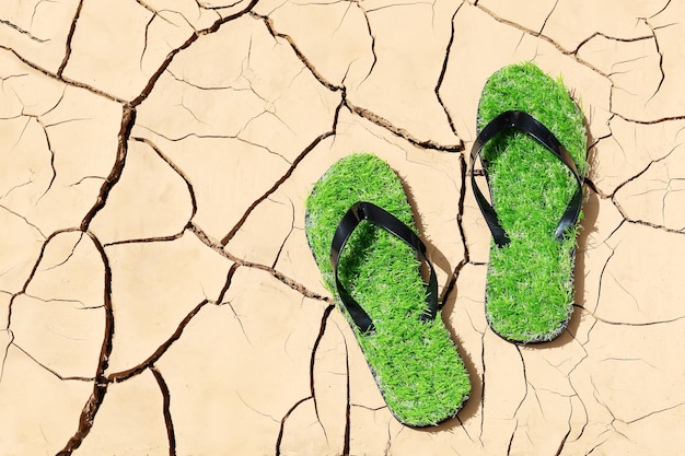 Erosión del suelo zapatillas verdes con imitación de hierba concepto de problemas ambientales de sequía