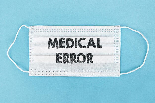 ERROR MÉDICO escrito en una máscara médica blanca sobre fondo azul Concepto médico