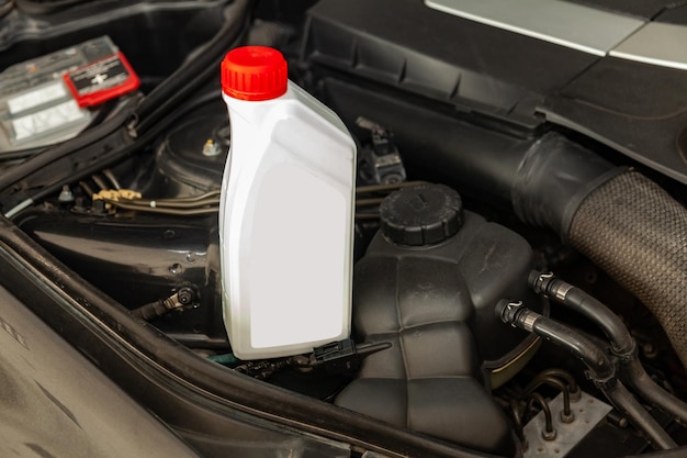 Ersatzteil für Automotor, 1-Liter-Flasche oder Dose Schmiermittel in Grau mit rotem Deckel auf einem Hintergrund mit Fach unter der Motorhaube, Wartung und Ölwechsel in der Automobilindustrie