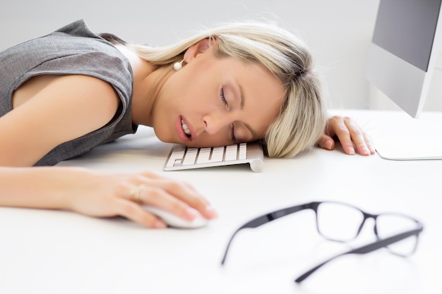 Foto erschöpfte frau, die vor dem computer schläft