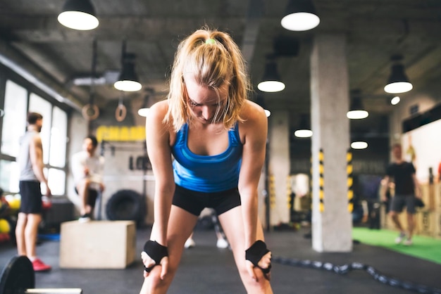 Erschöpfte junge Frau im Fitnessstudio, die eine Pause macht