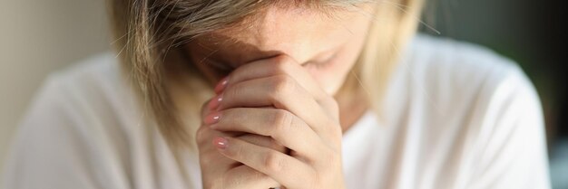 Erschöpfte und unglückliche Frau hält ihre Hände in der Nähe der Stirn verbunden, Nahaufnahmekonzept von