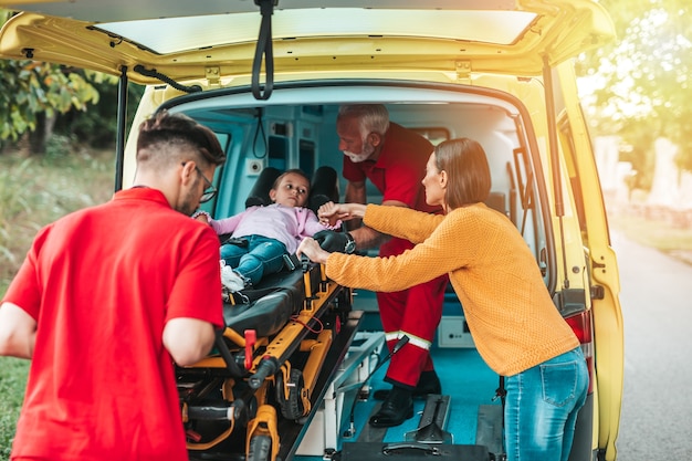 Erschrockene Mutter, die mit Ärzten und ihrer verletzten Tochter steht