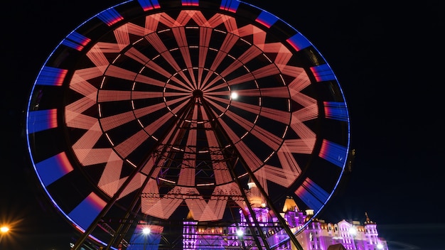 Erstaunlich beleuchtetes Riesenrad und Hotel "Bogatyr" nachts im Olympiapark von Sotschi, Russland.