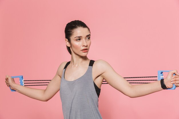 erstaunlich schöne junge hübsche Fitness-Frau macht Sportübungen mit Ausrüstung über rosa Wand isoliert?