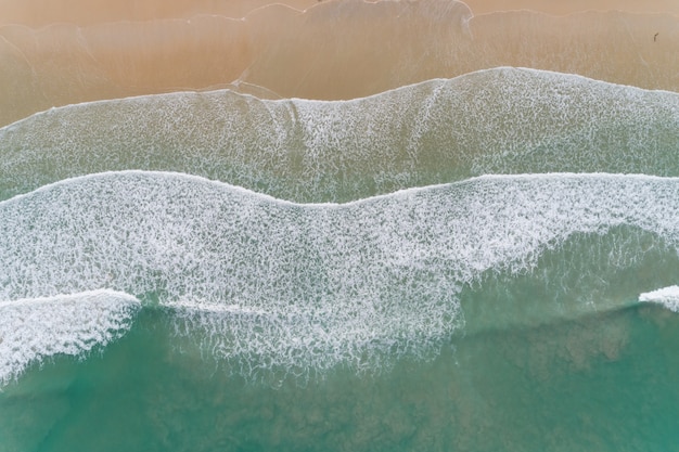 Erstaunliche Ansicht Luftbild Drohnenkamerafoto von Wellen, die am sandigen Ufer abstürzen, Draufsicht des schönen Sandstrandes im Morgensonnenaufgang.