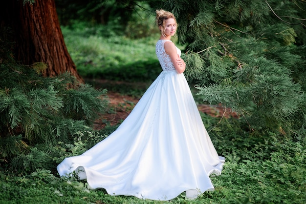 Erstaunliche Braut im eleganten Kleid wirft im grünen Park auf