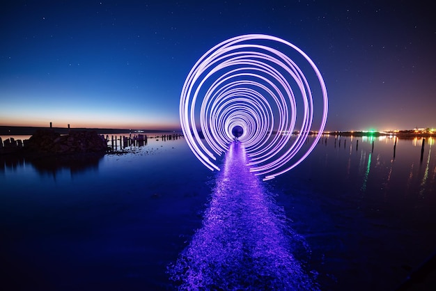 Erstaunliche laser-feuershow-performance am nachtblauen himmel mit reflexionen im meerwasser