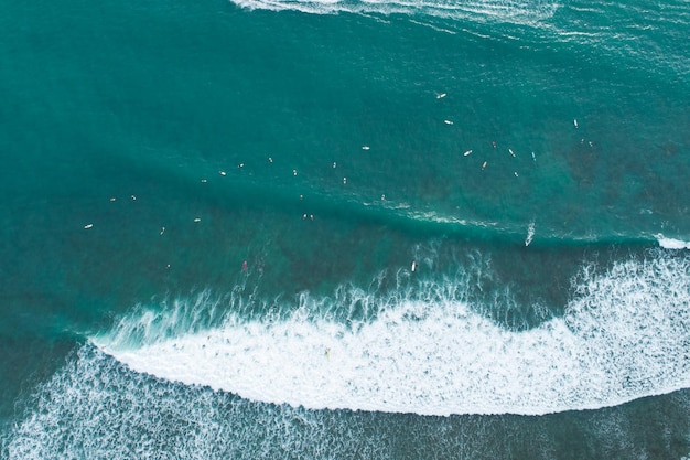 Erstaunliche Luftaufnahme Von oben nach unten brechen die Wellen auf dem tropischen Meer Surfer mit Surfbrettern Luftdrohnenansicht der Meereswellen auf dem wunderschönen Ozean in Phuket Thailand.