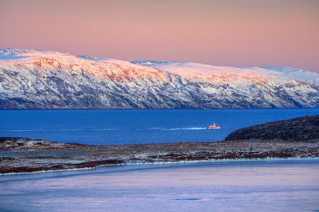 Erstaunliche Sonnenaufgang-Polarlandschaft mit weißer schneebedeckter Bergkette am Horizont. Wunderbare Berglandschaft auf der Barentssee. Teriberka.