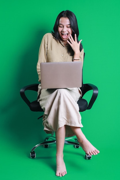 Erstaunliche weibliche Unternehmerin mit Zahnspange, die online mit einem Laptop arbeitet, isolierter grüner Hintergrund