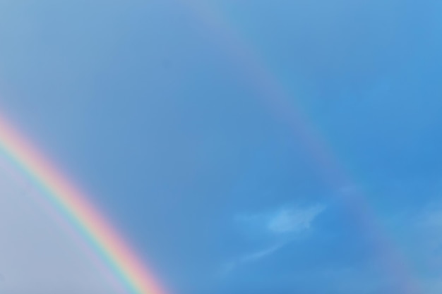 Erstaunlicher bunter doppelter Regenbogen im blauen Himmel an einem regnerischen Tag