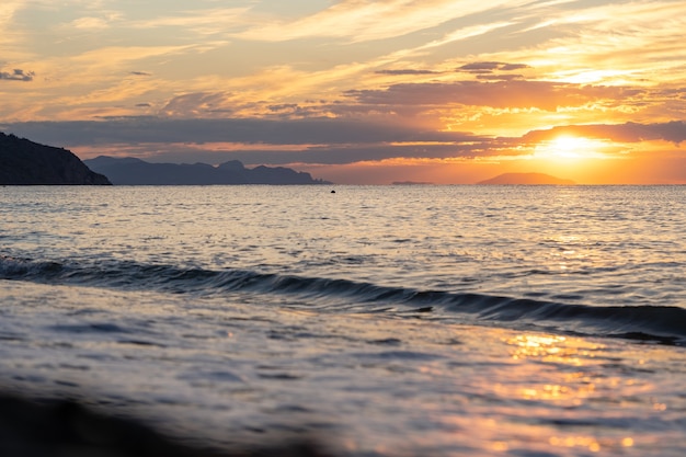 Erstaunlicher Sonnenaufgang über dem tropischen Strand. Gelbe Sonne über Meer. Orangefarbene Wellen. Natur Hintergrund. Schöne ruhige Szene. Morgen. Sonnenlicht reflektiert auf der Wasseroberfläche