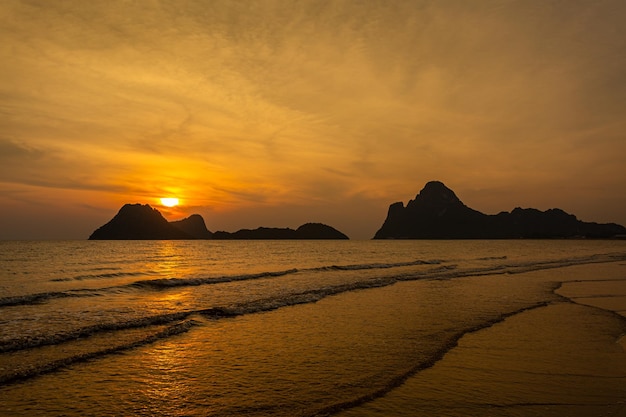 Erstaunlicher Strandsonnenuntergang mit endlosem Horizont und einsamen Gestalten in der Ferne und unglaublich schäumendem W