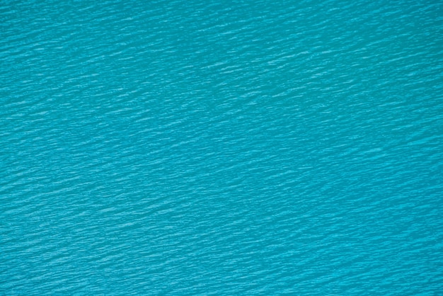 Erstaunlicher strukturierter Hintergrund der ruhigen azurblauen sauberen Wasseroberfläche. Sonnenschein im Bergsee hautnah.