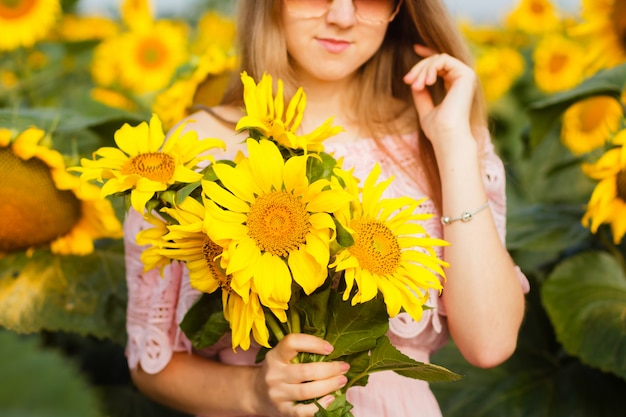 Erstaunliches Foto, schöne junge blonde Frau, die unter Sonnenblumen steht