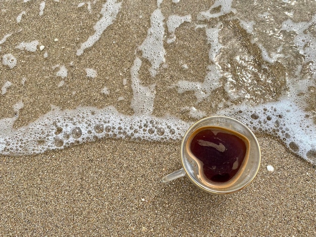 Erstaunliches Konzept für einen Tag in der Nähe des Meeres. Selektiver Fokus auf eine Tasse Kaffee in der Nähe des Meeres