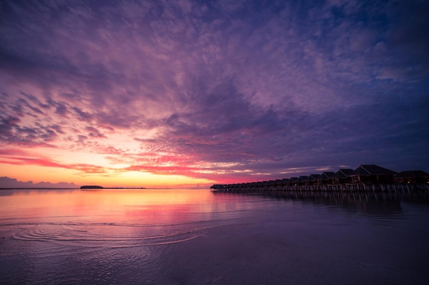 Erstaunliches Sonnenuntergangspanorama auf den Malediven. Luxus-Resort-Villen Meereslandschaft Bucht Schönheit Reflexion der Meeresoberfläche