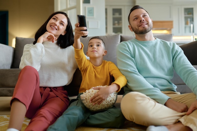 Erstaunte Eltern und neugierige Kinder, die zu Hause Fernsehprogramme ansehen