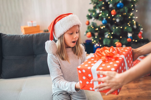 Erstauntes Kind hält Geschenk und schaut es an. Sie hält den Mund offen.