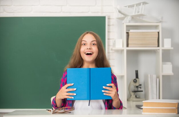 Erstauntes Kind macht Hausaufgaben mit Buch. Teenager-Student. moderne Bildung. weiterführende Schule