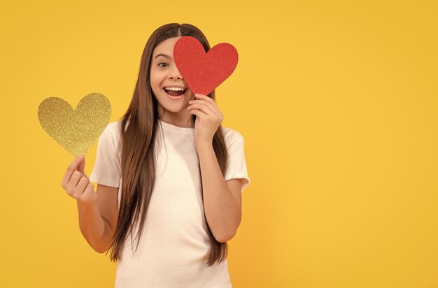 Erstauntes Kind mit rotem Herzen auf gelbem Hintergrund Valentinsgrußverkauf