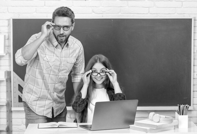 Erstauntes Kind und Vater, die im Klassenzimmer mit Computer beim E-Learning an der Tafel sitzen