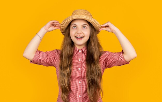 Foto erstauntes mädchen mit strohhut auf gelbem hintergrund