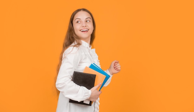 Foto erstauntes teenager-mädchen läuft mit schularbeitsbuch auf gelben hintergrund kopieren raum kindheit