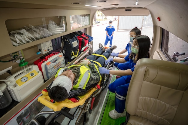 Foto erste-hilfe-schulung zum transfer des patienten, gefühlsverlust oder verlust der normalen bewegung. sanitäter-team transferiert mann auf krankenwagen-bahre in notwagen.