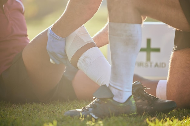 Foto erste-hilfe-sportverletzung und hände am bein bei rugby-unfall, fitness und massage auf einem feld, trainingstraining und physiotherapie bei knieschmerzen beim spiel, mit medizinischem notfall durch training