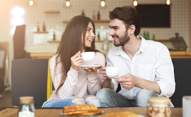 Erste Verabredung. Nettes Paar, das sich im Café anschaut und Morgenkaffee trinkt, Kopierraum