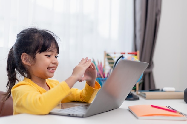 Erster Schultag Asiatisches kleines Mädchen mit einem Laptop, das über ein Online-E-Learning-System lernt