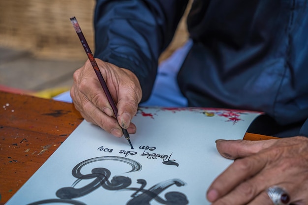 Un erudito vietnamita que usa Ao Dai escribe caligrafía El festival de caligrafía es una tradición popular durante la festividad del Tet Escribir coplas para el Año Nuevo del Festival de Primavera