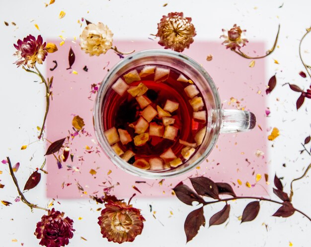 Erva Bellis seca com flores e chá na superfície cinza e rosa isolada. Sem sombras