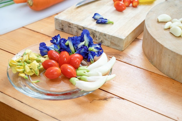 Erva de flor da Tailândia para decoração de comida flor borboleta borboleta tometos no prato de vidro no balcão de madeira e placa ao lado na cozinha temática da Ásia