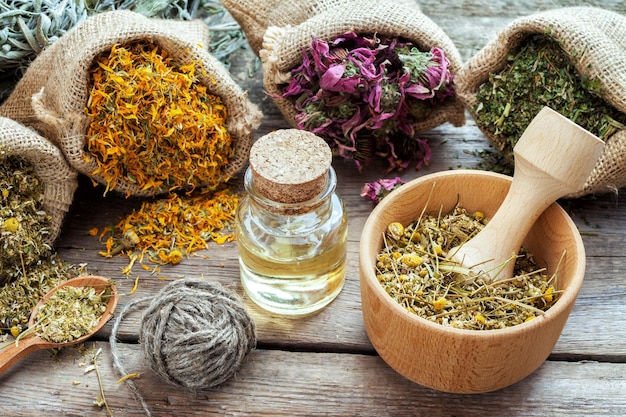 Ervas curativas em argamassa de sacos hessianos de camomila e óleo essencial em ervas medicinais de mesa de madeira