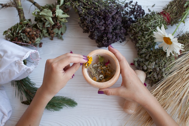 Ervas secas e flores em argamassa branca sobre tábua rústica, decoração de verão, fitoterapia