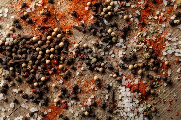 Ervilhas de pimenta preta e branca sal marinho pimenta vermelha cravo especiarias em um fundo de madeira