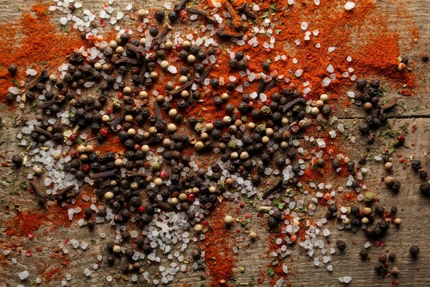 Ervilhas de pimenta preta e branca sal marinho pimenta vermelha cravo especiarias em um fundo de madeira
