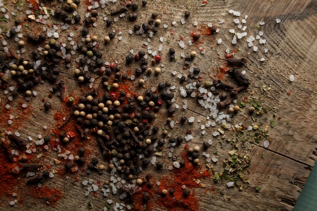 Ervilhas de pimenta preta e branca sal marinho pimenta vermelha cravo especiarias em um fundo de madeira