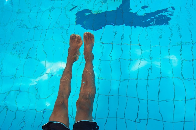 Erwachsene Afroamerikaner mans Beine unter Wasser im Schwimmbad